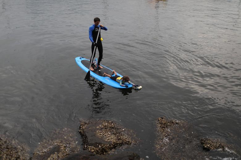 Bức ảnh chụp Nina Gomes nhặt chai nhựa nổi trên mặt nước khi đi cùng cha của bé.