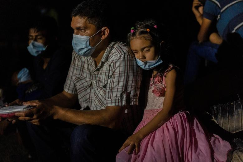 Một em nhỏ tựa đầu vào vai cha ngủ trong khi chờ lực lượng tuần tra biên giới Mỹ giải quyết ở Roma, Texas, ngày 29/7.