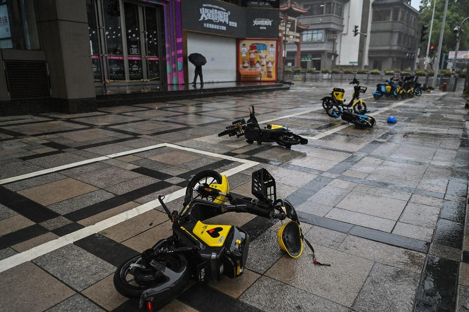 Công ty giải trí Disneyland ở Thượng Hải đóng cửa từ ngày 25-26/7 vì thời tiết xấu. Theo Tân Hoa Xã, cảng Dương Sơn ở thành phố này cũng phải sơ tán hàng trăm tàu thuyền để tránh bão. Trong ảnh, xe đạp điện bị gió bão thổi bay ở tỉnh Chiết Giang hôm 25/7. Ảnh: AFP.