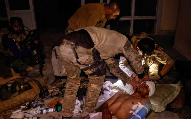 Đặc nhiệm Afghanistan giúp đỡ một binh sĩ quân đội nước này bị thương trong cuộc giao đấu với Taliban ở Kandahar hôm 12/7.