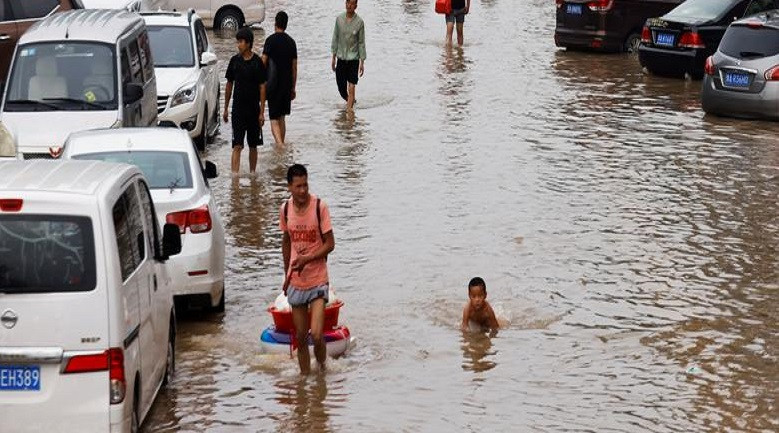 Một em nhỏ "bơi" trên con đường ngập lụt ở Trịnh Châu.