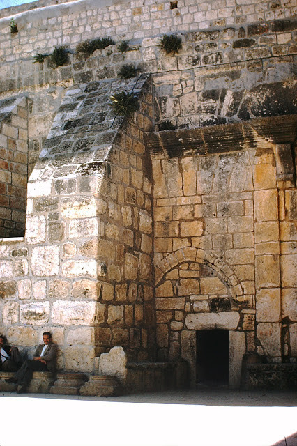 Một người đàn ông ngồi nghỉ bên ngoài kiến trúc cổ ở Jerusalem.