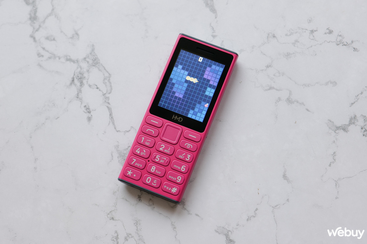 HMD 105 4G có thiết kế nhỏ gọn, với trọng lượng chỉ 92,99g và kích thước vừa phải, giúp người dùng dễ dàng cầm nắm. Màn hình 2,4 inch với độ phân giải QVGA cung cấp hình ảnh rõ ràng, mặc dù lớp kính bên ngoài dễ bị phản chiếu ánh sáng, gây khó khăn khi sử dụng dưới trời nắng gắt.