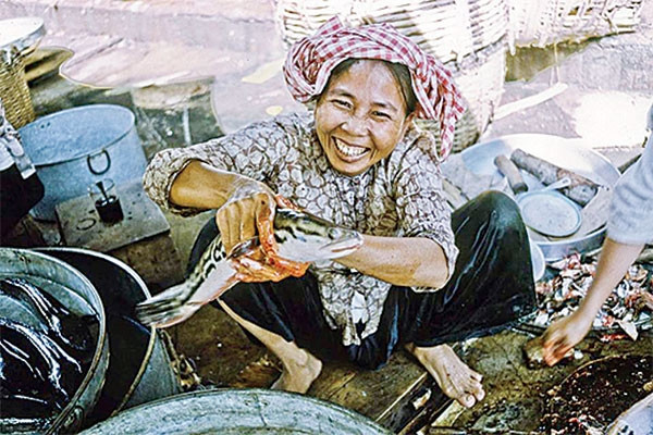 Người phụ nữ bán cá cầm trên tay con cá tươi rói.