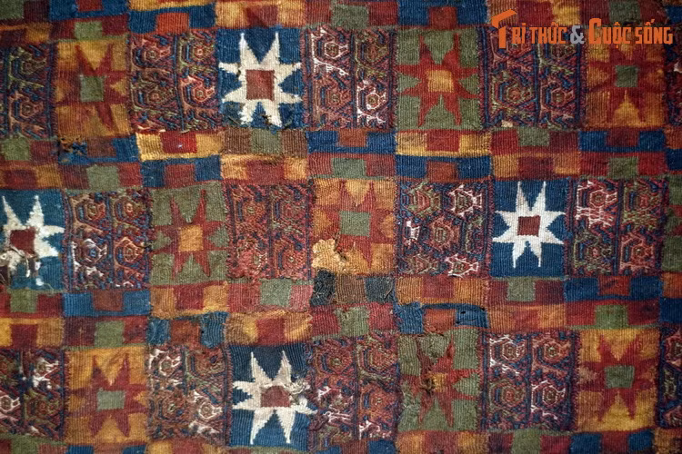 Mảnh tấm choàng làm bằng vải sợi len, hoa văn dệt của văn hóa Chimu (1100-1463). Họa tiết trên vải mô phỏng đầu chùy hình ngôi sao đặc trưng của văn hóa Inca (1450-1532). Những họa tiết nhỏ là mô-típ Chimu truyền thống. Đồ vải của người Chimu thường được cài lông chim và đáp vàng.