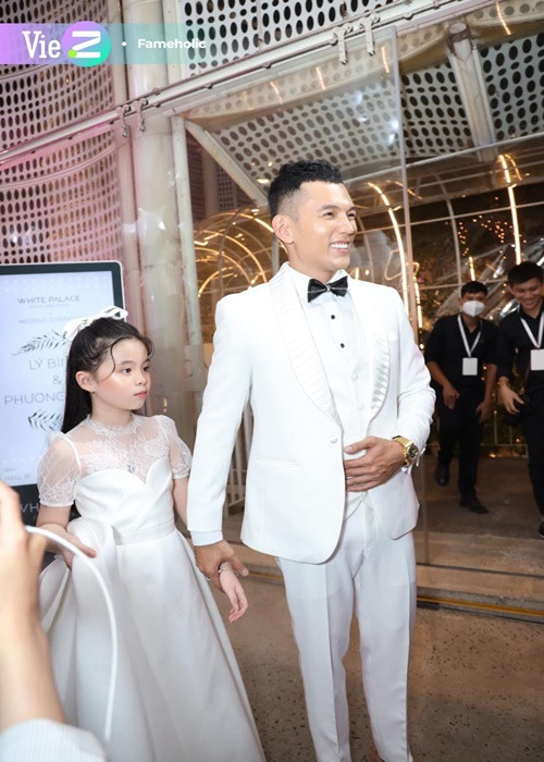 Trong đám cưới, Lý Bình luôn nắm chặt tay bé Mia, che chắn Mia phía sau lưng mình, tránh ống kính và những người qua lại đông đúc. Ảnh: VietZ