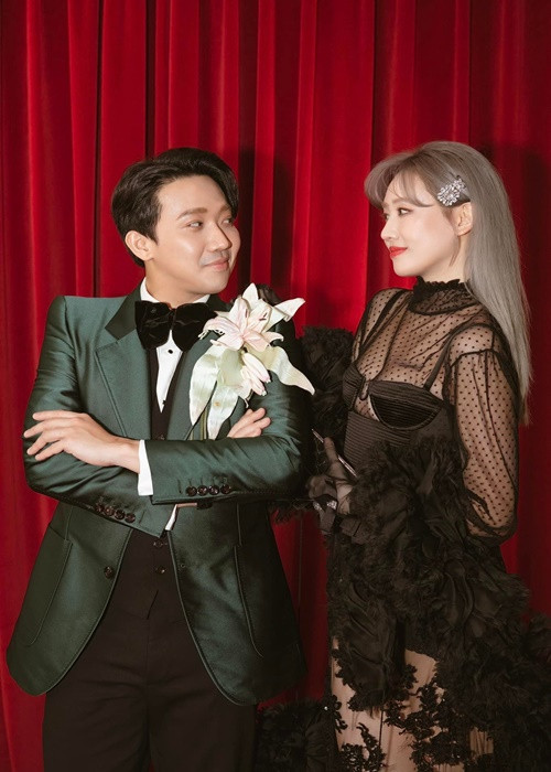 Nữ ca sĩ khoe tóc chuyển sang màu xám khói bên Trấn Thành tại một sự kiện.