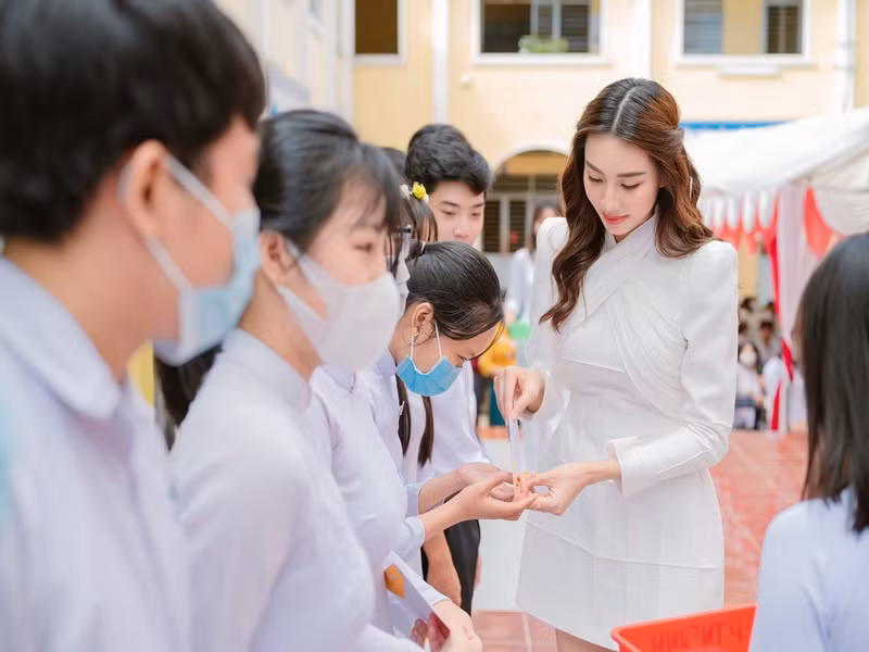 Có mặt tại trường THPT Châu Phong, Hoa hậu Hòa bình Quốc tế 20121 Thùy Tiên mặc chiếc váy trắng đơn giản.