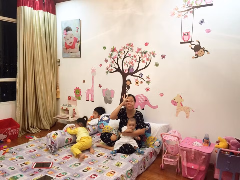 Mẹ Ốc tỉ mẩn dán đề-can trang trí phòng cho con.