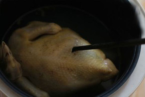 Để kiểm tra xem gà chín chưa, chỉ cần ngửa bụng gà ra và dùng đũa đầu nhỏ chọc nhẹ vào phần khe đùi con gà, nếu nước chảy ra có màu trắng trong thì gà đã chín, nước có chút màu hơi đỏ chảy ra thì luộc gà thêm chút nữa. Ảnh: tinnhanh247