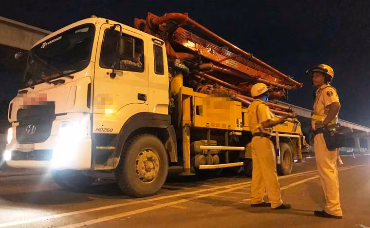 Một tài xế lái xe tải nặng hàng chục tấn chở dàn ống bơm hút cho công trình được CSGT kiểm tra...