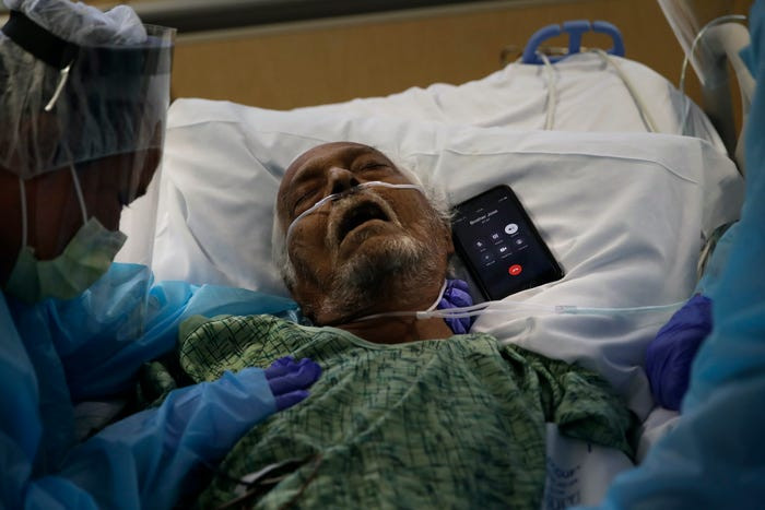Do các bệnh viện hạn chế hoặc cấm thân nhân vào thăm nên người thân của bệnh nhân COVID-19 sắp qua đời phải nói lời từ biệt qua điện thoại, iPad. Ảnh: Chiếc điện thoại được đặt cạnh Antonio Navarro, một bệnh nhân COVID-19 65 tuổi, để con trai ông, Jose, có thể nói lời tạm biệt, tại Trung tâm Y tế St.Jude ở Fullerton, bang California, Mỹ, ngày 31/7/2020.