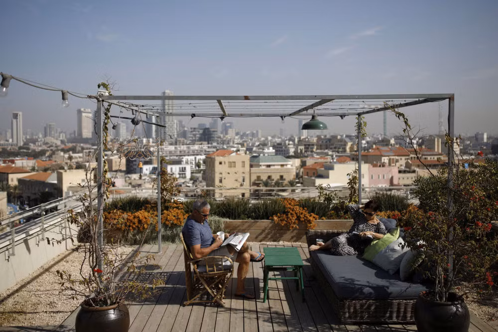 Moni Chorev, 60 tuổi, và vợ ông, Gilly, ngồi đọc báo, thưởng thức trà trên sân thượng.