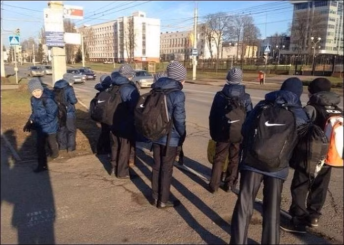 Các em học sinh mặc đồng phục “từ đầu đến chân” đứng chờ xe. Ảnh: ER.