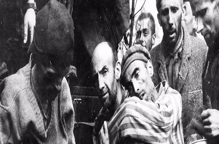 Một tù nhân sắp chết đói được bạn tù cõng tới bệnh viện ngày 4/5/1945. Ảnh: Ralph Forney.