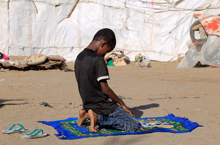 Ông Mohammed Ruzaiq, 67 tuổi, cho biết người dân Yemen không đòi hỏi sự cứu trợ từ bên ngoài mà chỉ mong muốn chiến tranh sẽ kết thúc. Ảnh: Bé Ayoub đang cầu nguyện bên ngoài túp lều tạm bợ của gia đình.