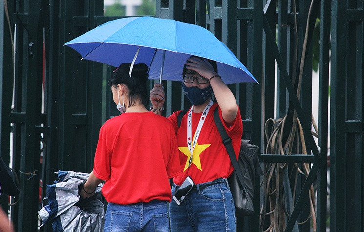 Cổ động viên mặc áo đỏ sao vàng, đội mưa đón Olympic Việt Nam tại sân vận động Mỹ Đình.