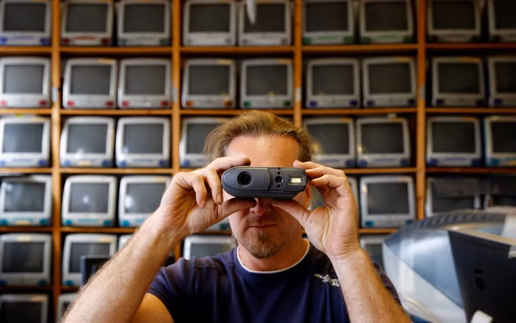 Roland Borsky xin hoặc mua lại những thiết bị mà người dùng không cần đến. "Cũng giống như những người có sở thích sưu tầm xe hơi hay nhiều thứ khác, đây là niềm đam mê của tôi", anh nói. Trong ảnh, Borsky đang cầm chiếc máy ảnh Quicktake ra đời năm 1994.