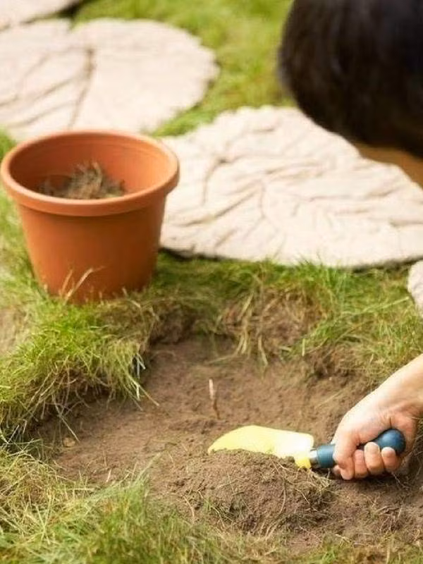 Để gạch lát chắc chắn, cậu bé cẩn thận đào trước một lớp đất vừa phải trước khi đặt tấm xi măng xuống.