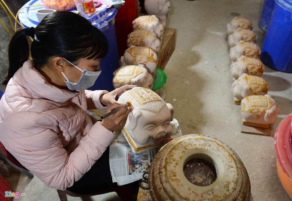 Một người thợ sẽ dùng bút bằng sáp nến để vẽ lên những hoa văn trên mình lợn. Sau đó, chúng được tráng men và nung thêm một lần nữa.