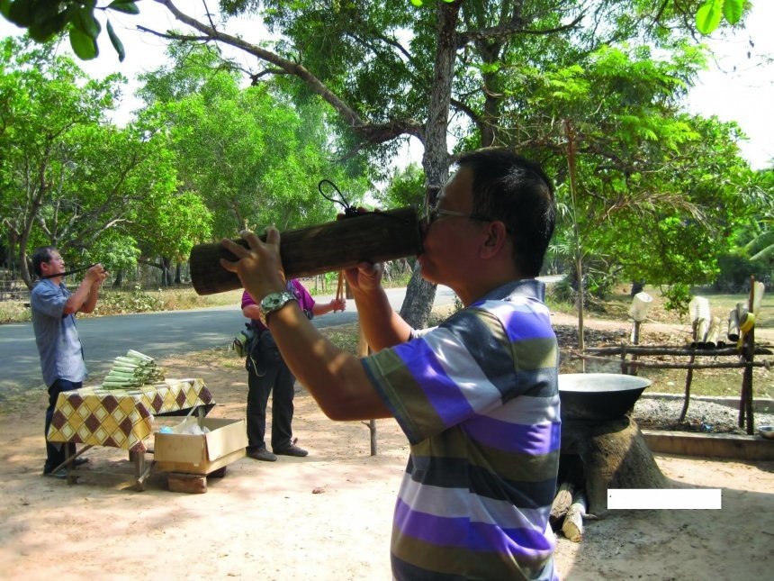 Du khách uống nước thốt nốt đựng trong ống lồ ô truyền thống.
