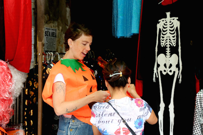 Một vị khách nước ngoài thích thú khi được mặc thử chiếc áo có hình quả bí ngô.