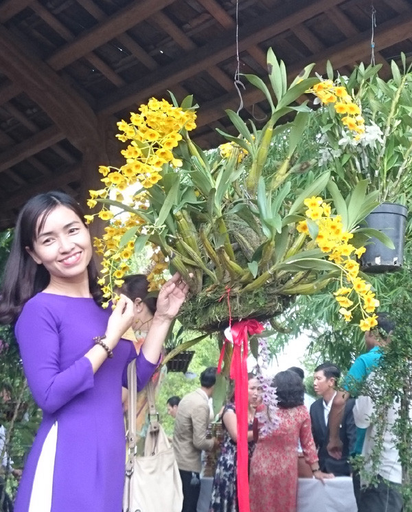 Người phụ nữ khoe sắc cùng loài lan được đặt tên "Sơn Thủy Tiên". Ảnh: Trần Hòe.