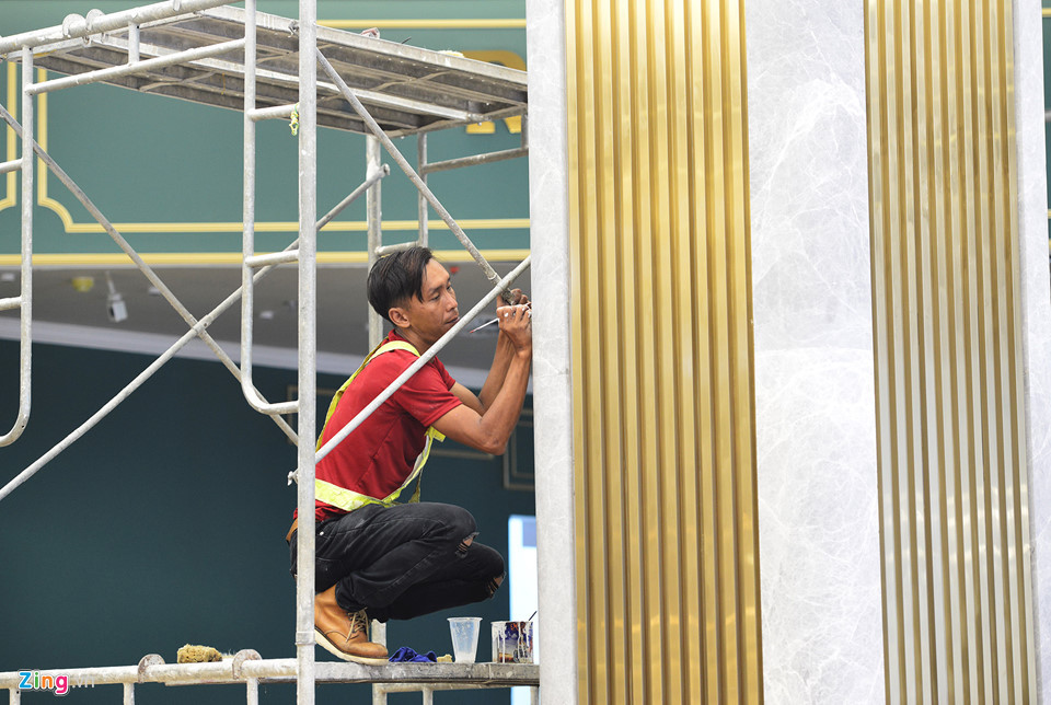 Công nhân hoàn thiện kiến trúc cột trụ được ốp bằng đá giữa các sảnh của tầng trệt.