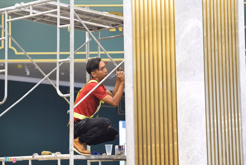 Công nhân hoàn thiện kiến trúc cột trụ được ốp bằng đá giữa các sảnh của tầng trệt.