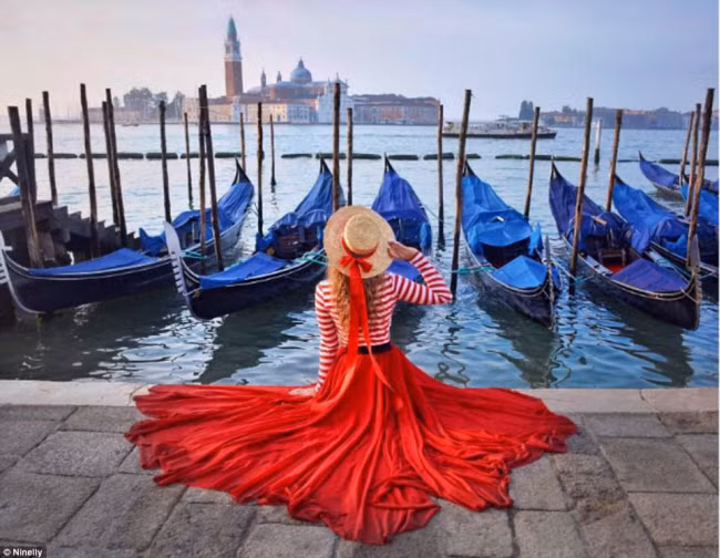 Cô gái đến từ Nga mặc trang phục đỏ lộng lẫy khi đứng bên dòng kênh ở thành phố Venice, Italia.