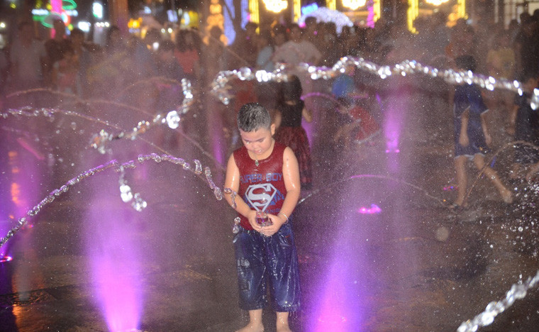 Bé trai vô tư nghịch nước trên phố đi bộ Nguyễn Huệ dù đang ở giữa mùa đông.