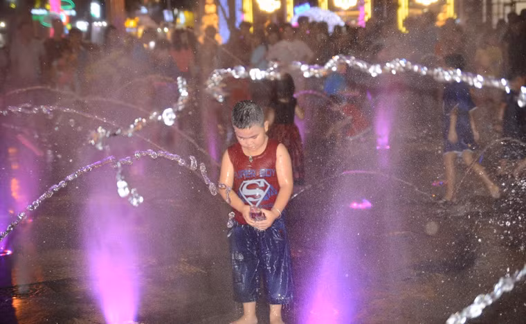 Bé trai vô tư nghịch nước trên phố đi bộ Nguyễn Huệ dù đang ở giữa mùa đông.