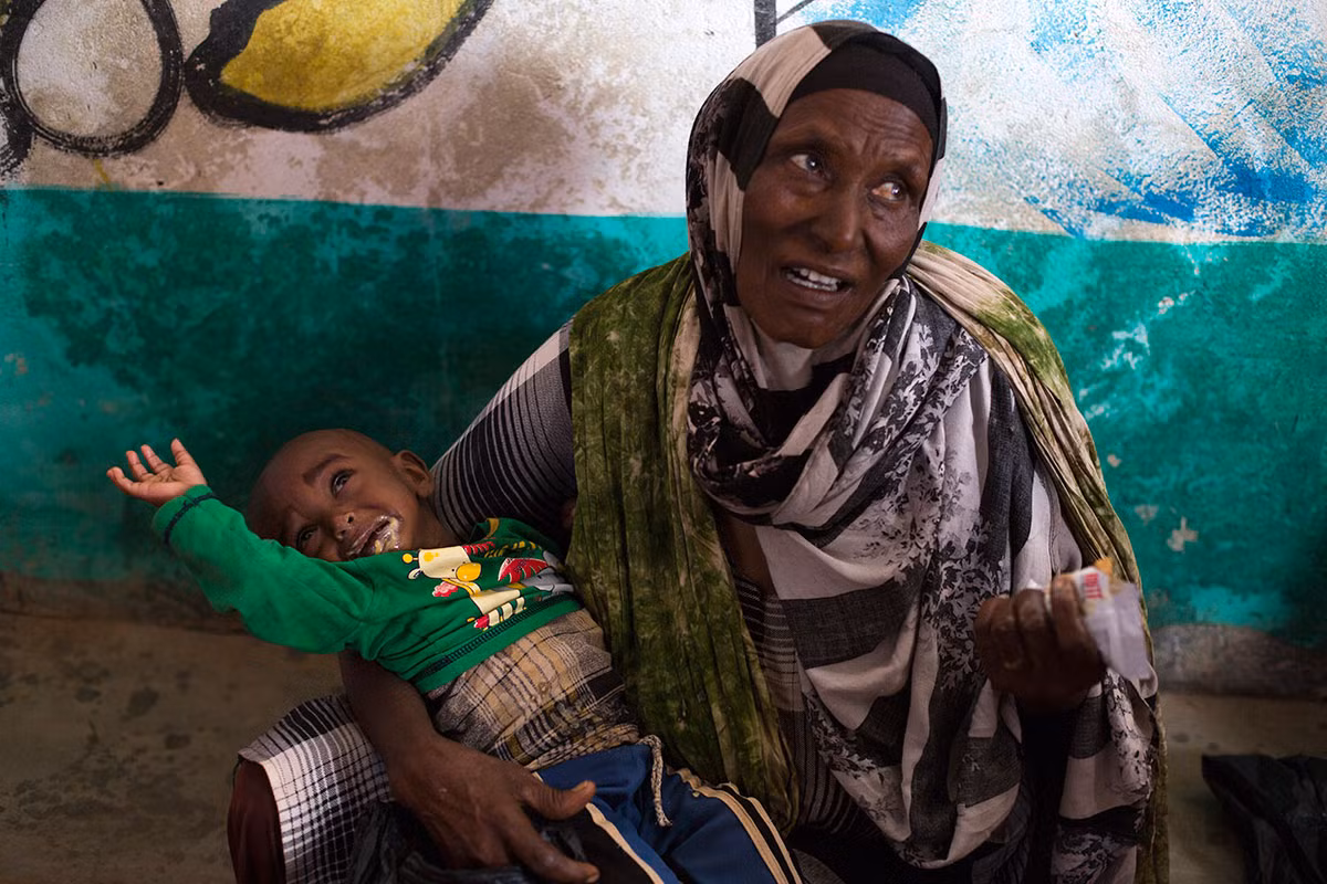 Habibo Ali đang cho cháu trai Abdi Karim ăn. Các em nhỏ sẽ được cân và kiểm tra sức khỏe tại phòng khám này.