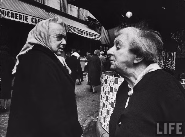 Hai cụ già trò chuyện khi gặp nhau trên đường phố Paris.