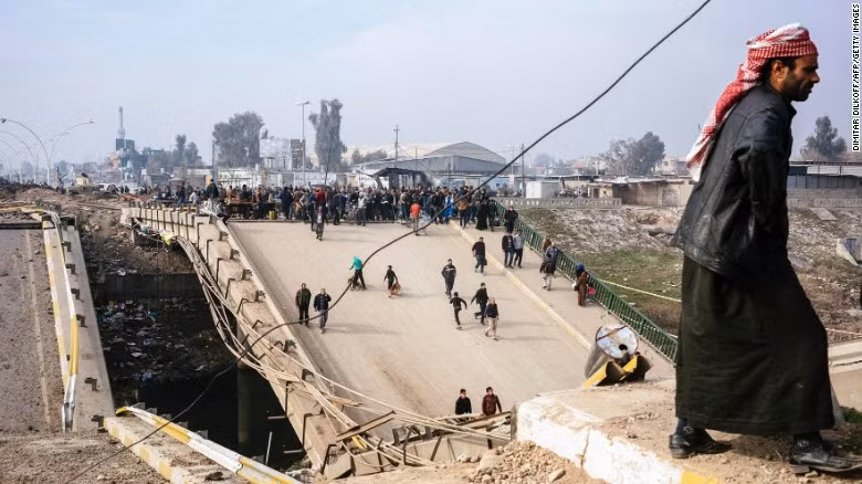 Các cư dân Mosul đi qua một cầu bị hư hại ở al-Sukkar ngày 21/1/2017. Được biết, khu vực Đông Mosul đã được giải phóng khỏi tay nhóm IS hồi tháng 1/2017. 