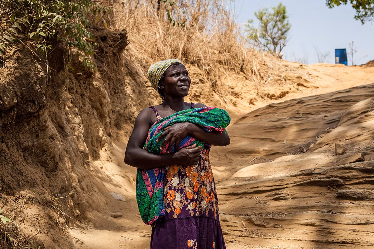 Được biết, Bắc Uganda trở thành nơi tiếp nhận chính những người tị nạn đến từ Nam Sudan kể từ khi cuộc nội chiến nổ ra tại quốc gia châu Phi này vào năm 2013 và tình trạng bạo lực gia tăng hồi tháng 7/2016. Ảnh: Một phụ nữ bế con nhỏ băng qua dòng suối Kaya – biên giới giữa Kajo-Keji (Nam Sudan) và Moyo (Uganda).