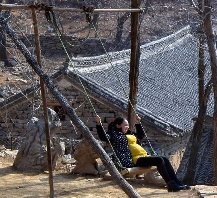 Nữ du khách thích thú khi ngồi trên xích đu trong ngôi làng đá ở tỉnh Hà Nam.