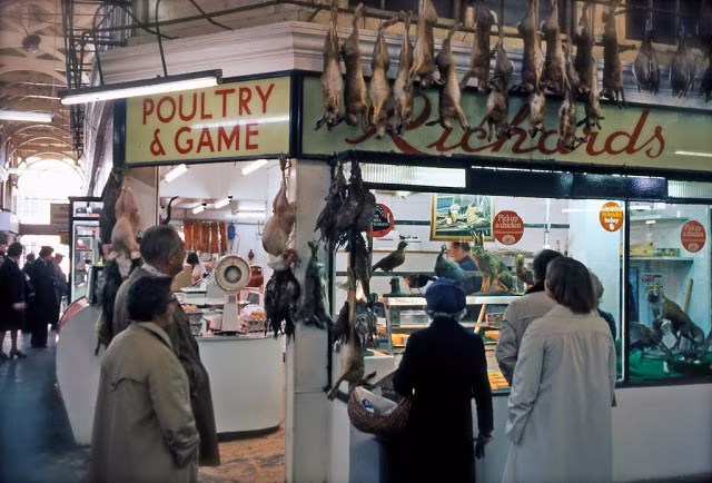 Nhiều người dường như đang đứng chờ trước một cửa hàng thực phẩm.