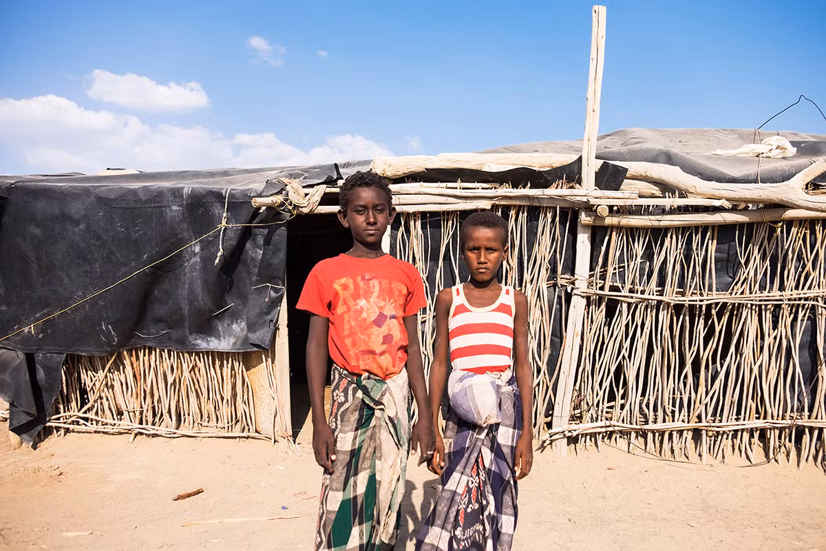 Hai em nhỏ đứng bên ngoài túp lều trong ngôi làng gần núi lửa Erta Ale, nơi được mệnh danh là cổng địa ngục ở Ethiopia.