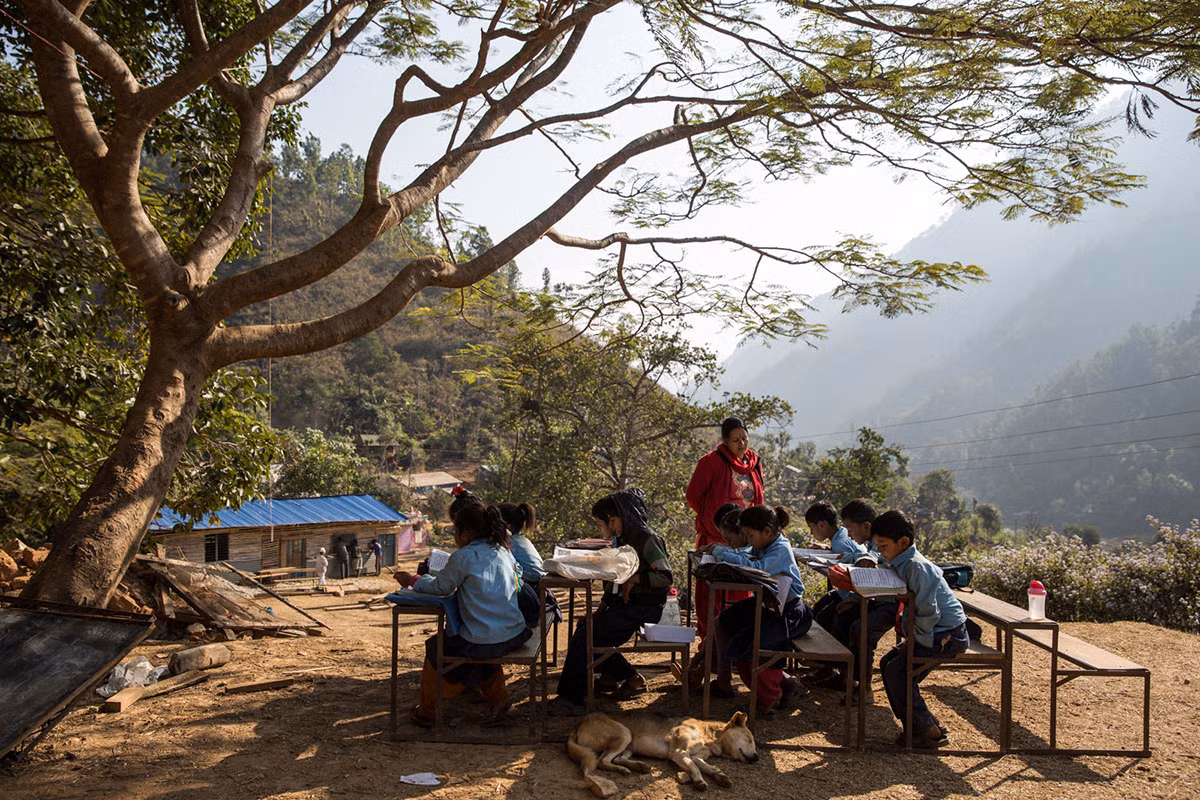 Các em nhỏ học ngồi học ngoài trời ở Trường Tiểu học Shree Arunodaya, làng Dandagaon. Được biết, ngôi trường này cũng đã bị hư hại nghiêm trọng trong trận động đất cách đây gần hai năm.