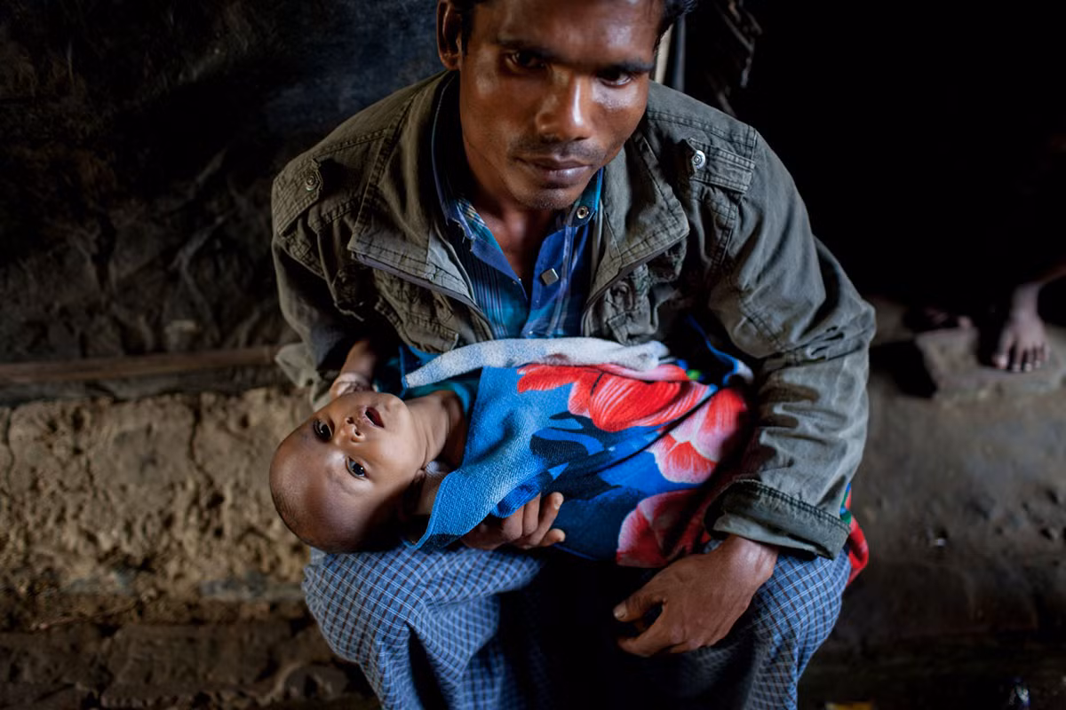 Mohammad Rafiq, 24 tuổi, đang bế cậu con nhỏ 8 tháng tuổi trên tay trong khu trại. Được biết, vợ anh đã qua đời.