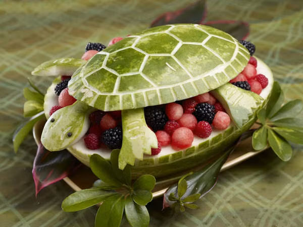 Một trái dưa đã được tỉa khéo léo thành hình chú rùa, bên trong trái đựng đủ các loại hoa quả ngon mắt.