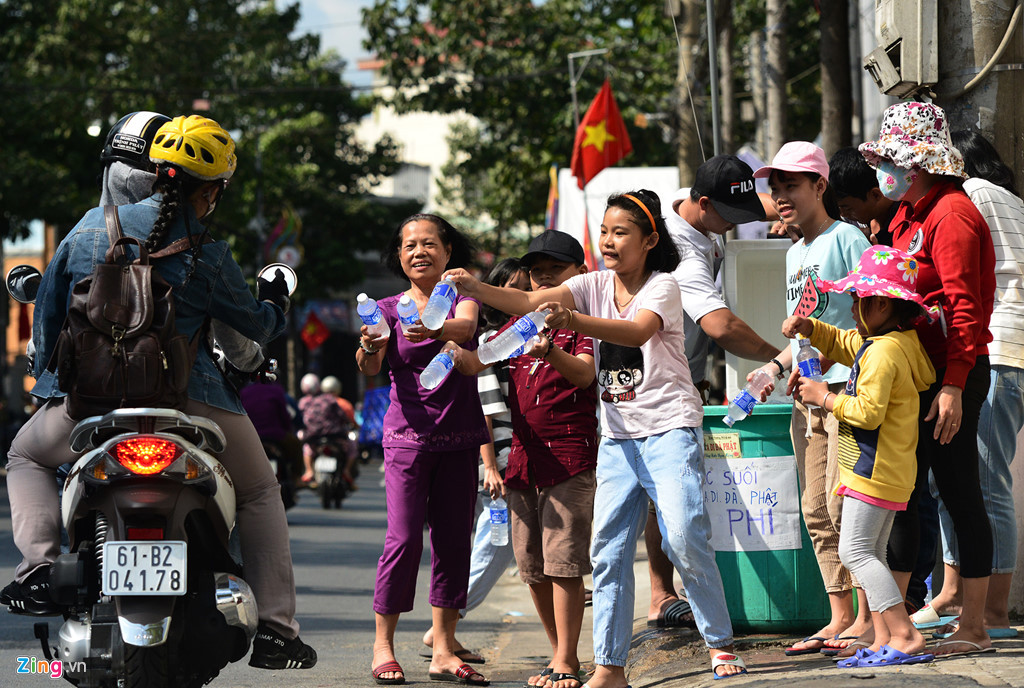 Trên đường Thích Quảng Đức, hàng chục già trẻ, con cháu gia đình anh Nguyễn Hồng Khanh (phường Hiệp Thành) đội nắng liên tục phát hơn 40 lốc nước suối ướp lạnh cho khách.