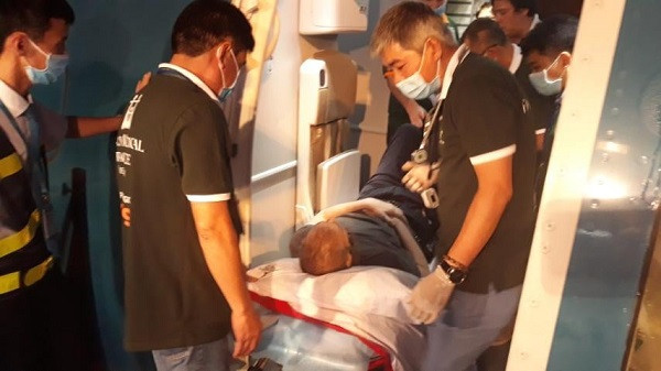 Bệnh nhân 91 nằm trên cáng y tế và được nhân viên di chuyển lên máy bay.