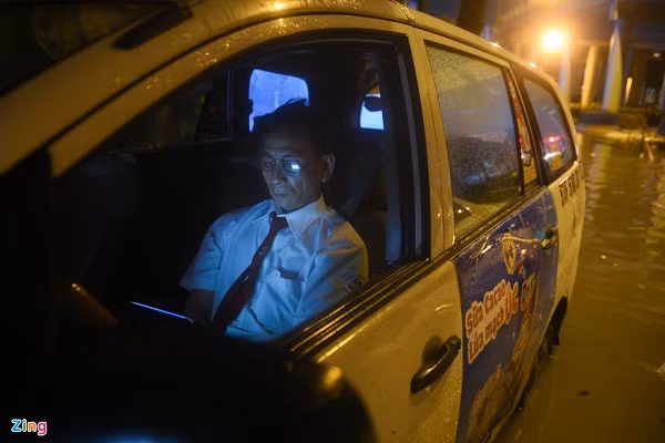 Ông Vũ Văn Thư vẫn ngồi trên xe taxi 7 chỗ đọc tin tức trên mạng. Ông cho hay ôtô không bị chết máy nhưng vẫn ngồi chờ đến khi nước rút xuống còn khoảng 30 cm thì mới yên tâm di chuyển qua đoạn ngập.