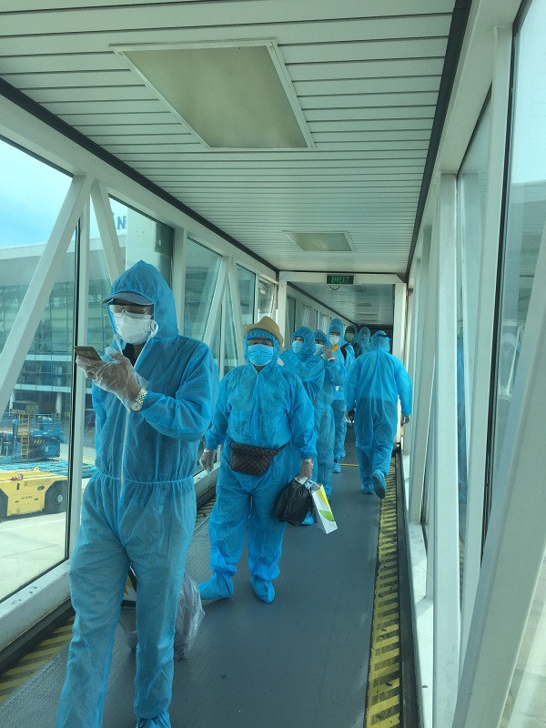 Hành khách mặc đồ bảo hộ, hành lý được bọc nilon chuẩn bị lên máy bay về Hà Nội.