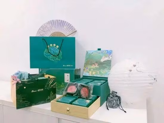 Hộp quà dịp Trung thu của tập đoàn Sina có màu xanh lá cây đậm, là loại hộp kéo hai lớp, đi kèm hai mặt búp bê đặc trưng và thiệp chúc mừng.