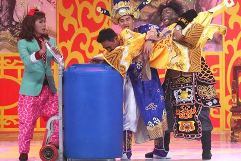 Trong Táo quân 2014, Quốc Khánh đóng vai người dân bị Nam Tào dìm đầu vào thùng nước, bị dọa nạt, đánh đập để mô phỏng lại vụ bảo mẫu bạo hành trẻ em. Ảnh: VTV.