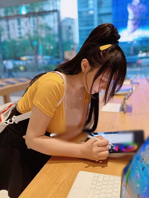 Cúi người sử dụng máy tính bảng khi đi mua sắm, Janie để lộ vòng một quyến rũ.