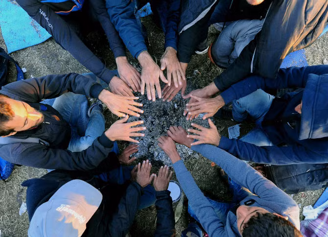 Người tị nạn sưởi ấm tay trong một khu tập trung dành cho di dân ở làng Roszke trên biên giới Hy Lạp – Serbia ngày 8/9.